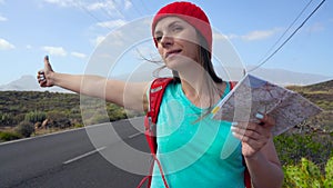 Traveler woman hitchhiking on a sunny road and walking. Backpacker woman looking for a ride to start a journey on a