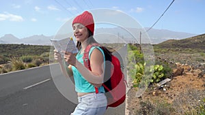 Traveler woman hitchhiking on a sunny road and walking. Backpacker woman looking for a ride to start a journey on a