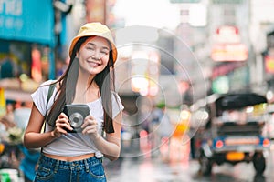 Traveler woman with instant camera in bangkok city