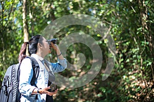 Traveler woman look binoculars on the forest,