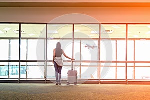 Traveler woman plan and backpack see the airplane at the airport glass window, girl tourist hold bag a