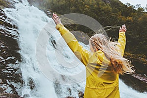 Traveler woman raised hands enjoying waterfall