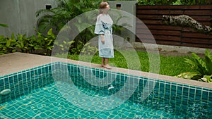 Traveler woman relaxing at villa in modern resort - walking along swimming pool