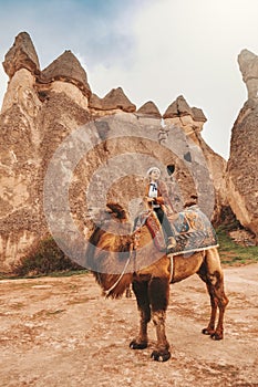 Traveler woman riding camel at Goreme fairy chimneys , Cappadocia. Nevsehir Province. Turkey