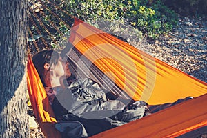 Traveler woman sleeping in a hammock on a rocky seashore