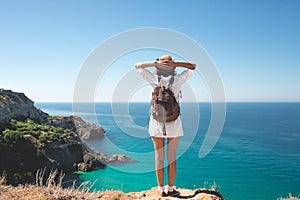 Traveler woman standing on sea cliff.