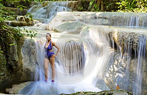 Traveler woman in swimsuit stand relax at Erawan Waterfall
