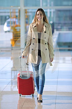 Traveler woman walking carrying a suitcase in an airport