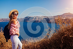 Traveler woman walking on Santorini island, Greece enjoying landscape. Happy girl enjoys Caldera view