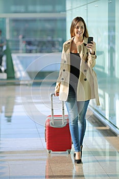 Traveler woman walking and using a smart phone in an airport photo