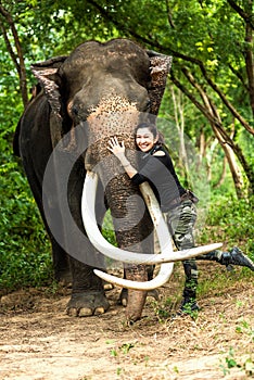 Traveler women backpack hug friendly with the wild elephant in the beautiful forest at Kanchanaburi province in Thailand for the t