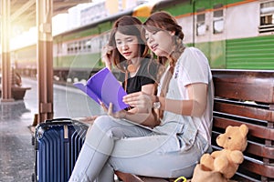 Traveler women and friends are looking and reading travel guide book for choosing tourism location to go travel together on