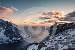 Traveler working a laptop on Ryten mountain on sunset at Lofoten Islands