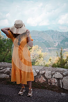 Traveler in yellow dress awed by majestic mountains