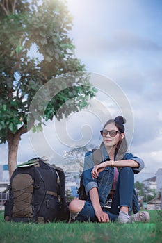 A traveler young girl sitting under a tree relax time and looing view place with a big bag photo
