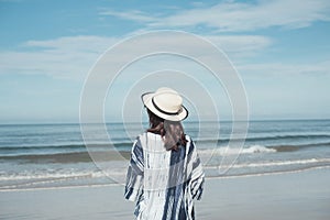 traveler young woman in casual dress with hat stand alone on beach has blue sky and sea background