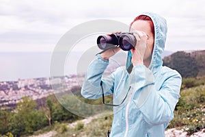 Traveler woman looking through binoculars outdoor.