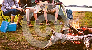 Travelers camping doing picnic and playing music in meadow field. Mountain and lake background. People and lifestyles concept.