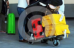 Travelers with colorful bags on trolley at airport