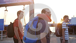 Travelers men walking to the ferry with backpacker during beautiful sunset and lens flare effects.