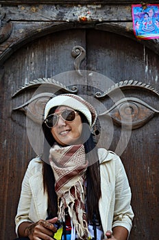 Travelers thai women journey and travel visit ancient art eyes of wisdom buddha on antique wooden wood door in nepali architecture