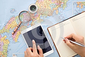 Travelers use iPad and notebook to make travel plans on Japan map