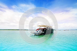 Travelers are walking up to the tour boat. The blur cool sea background on horizon tropical sandy beach; relaxing outdoors