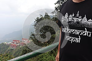 Travelers wear shirt that has temples of Kathmandu in Nepal printed on a dark black tshirt with white colored text print.