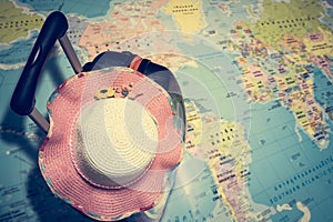 Traveling bag with straw hat on the world map