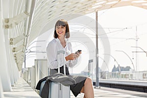Traveling business woman with suitcase and mobile phone
