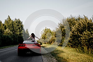 Traveling by car - happy couple in love go by cabriolet car in sunset time