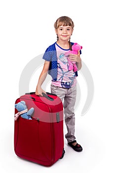 Traveling with children. Tourism. Cute little girl and big red suitcase isolated on white background