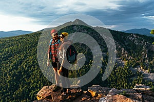 A traveling couple admires a beautiful sunset at the top of the mountain. A couple on the background of a mountain. Travelers