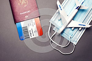 Traveling during COVID-19 virus, passport with airline ticket, medical mask and plane on grey background. Travel and health