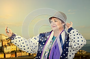 Traveling elderly woman takes selfie photo during highland tour