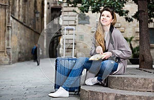 Traveling girl searching for the direction using a booklet in the town