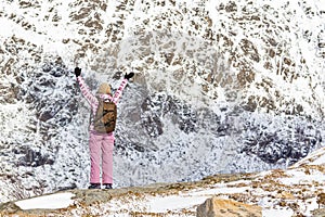 Traveling Ideas. Young Woman With Backpack and Outstratched Hands Standing on Mountain at Lofoten Islands in Norway