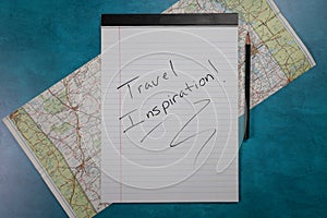 Traveling inspiration handwritten on notepad folded old road map in the background