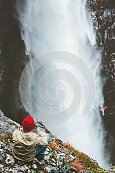 Traveling Man relaxing on cliff enjoying waterfall