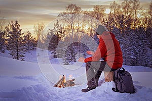 Traveling man  sitting  near camp fire and warm his hands