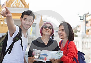 Traveling man woman and senior tourist holding travel guide book