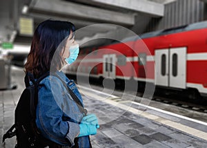 Traveling mature woman in a face mask watching for a train