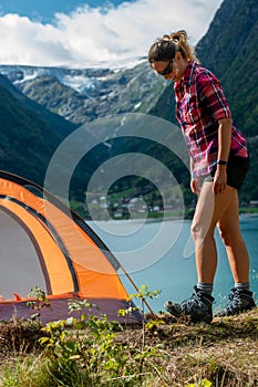 Traveling Norway, Young woman sets up tent, Beautiful view of Buerdalen Valley and Sandvevatnet Lake near city of Odda Norway