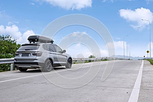 Traveling SUV car with roof box on highway against blue sky