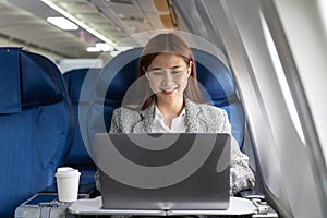 Traveling and technology. Flying at first class. Pretty young asian businees woman working on laptop computer while