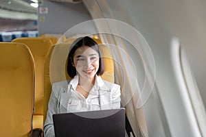 Traveling and technology. Flying at first class. Pretty young businees asian woman working on laptop computer while