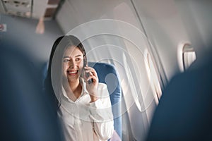 Traveling and technology. Flying at first class. Pretty young businees woman using smartphone while sitting in airplane.