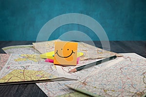 Traveling themed background old road maps scattered and folded happy face hand drawn on posted note