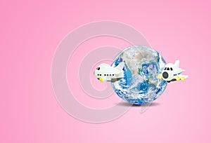 Traveling and Vacation Concept : Airplane flying around blue planet earth globe with pink background.