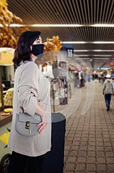 Traveling woman in a black face mask has entered an airport.